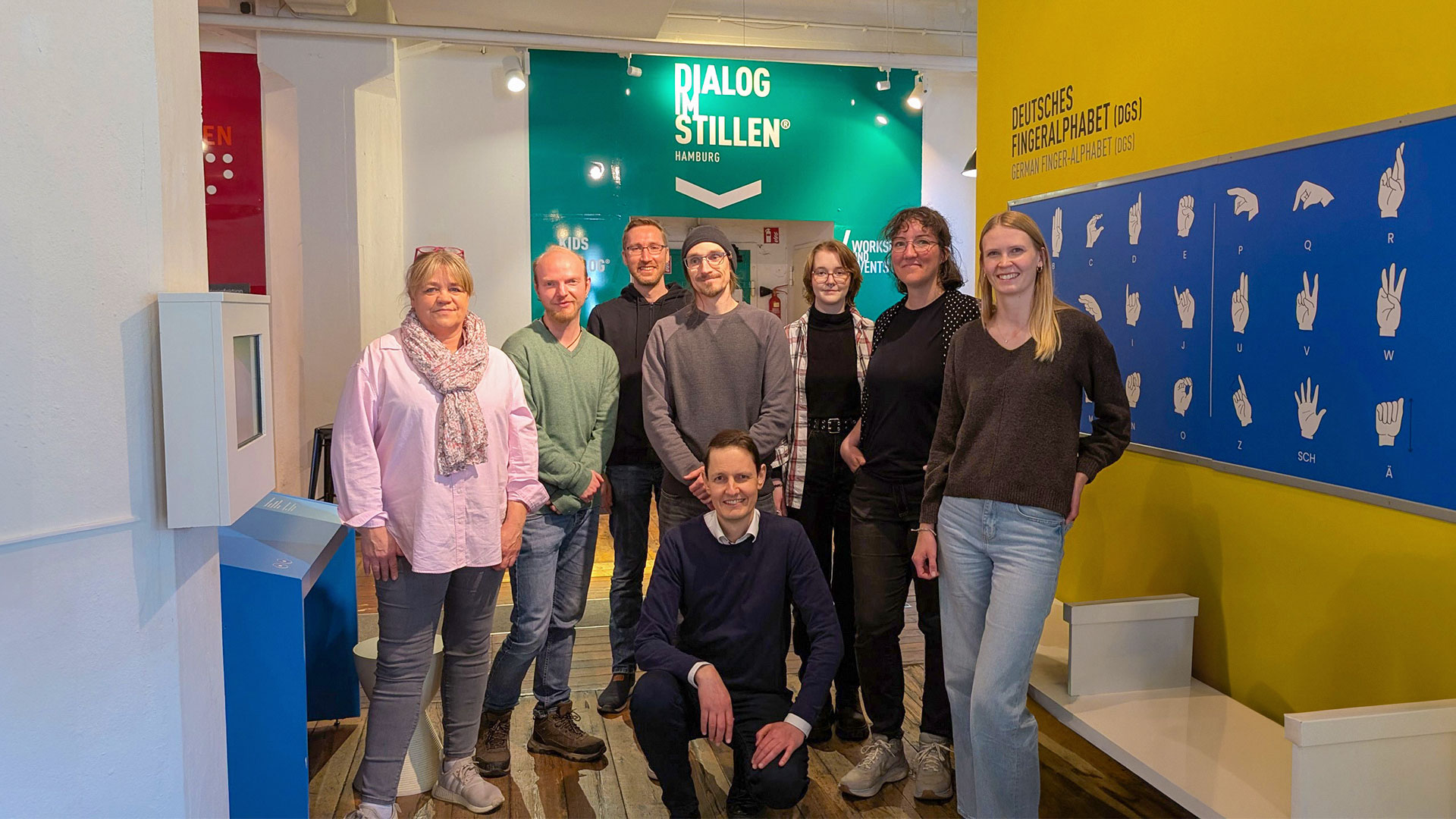 Teamfoto vor Ort am Eingang zur Ausstellung "Dialog im Stillen"